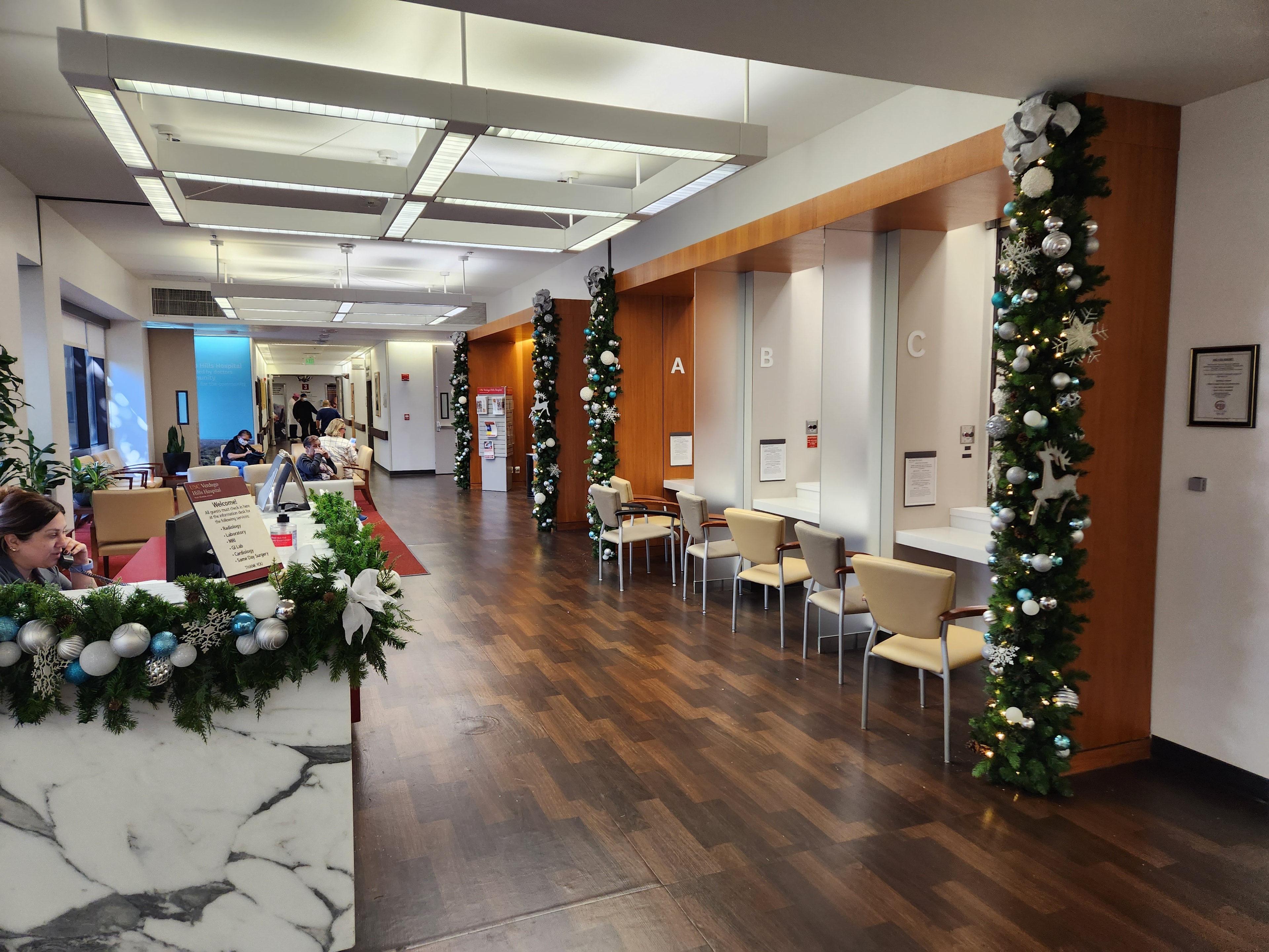 Hospital corridor with decorated columns and teal Christmas garland
